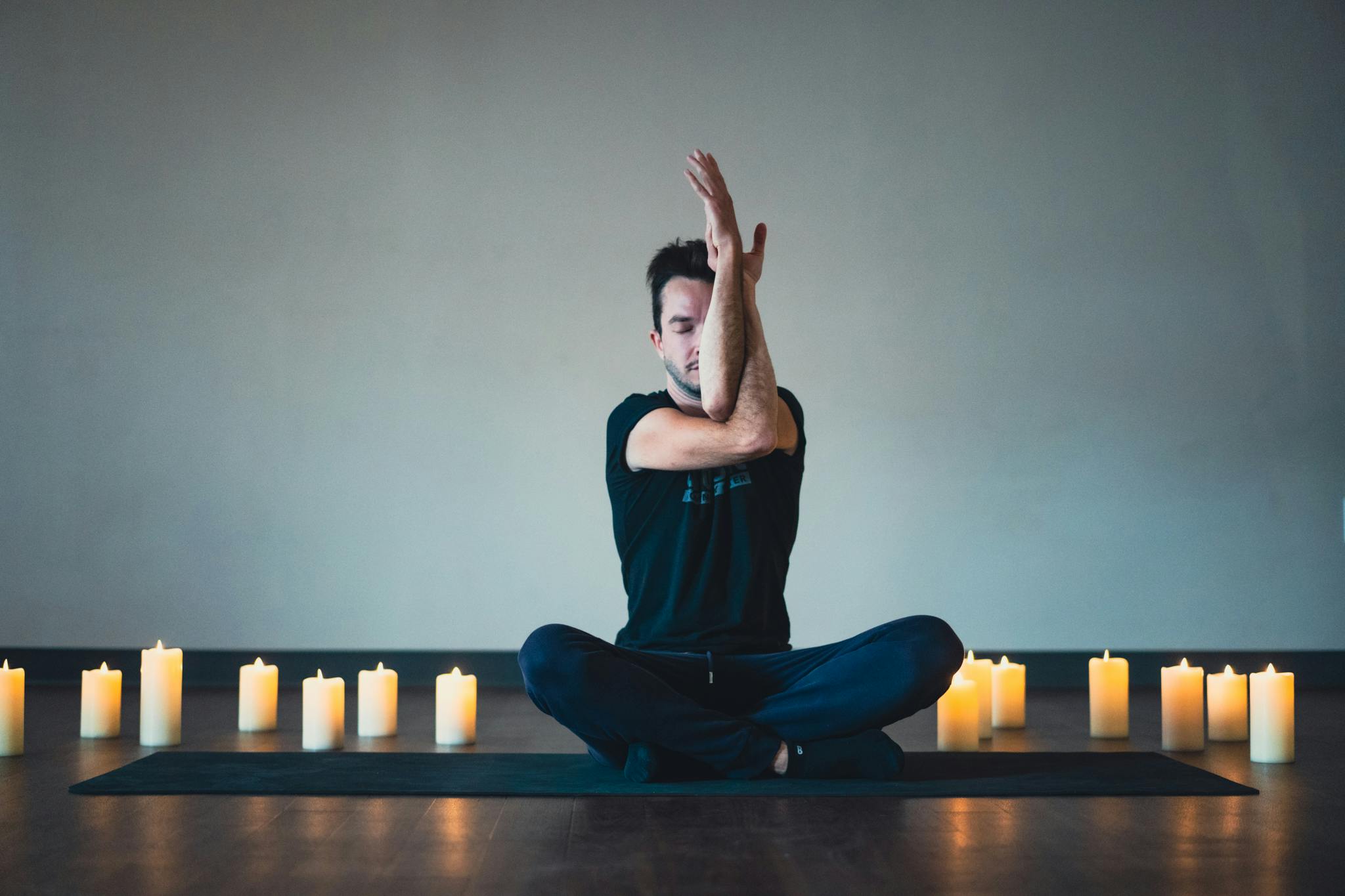 A guy doing yoga surrounded by candles.